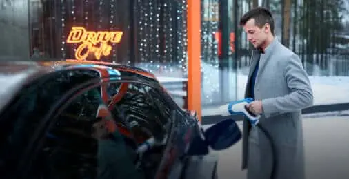 Автомобилист держит в руках зарядное устройство для электромобиля на АЗС сети «Газпромнефть»