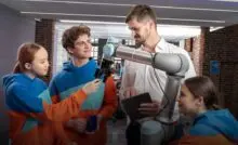 Молодые специалисты учатся управлять роборукой под присмотром наставника