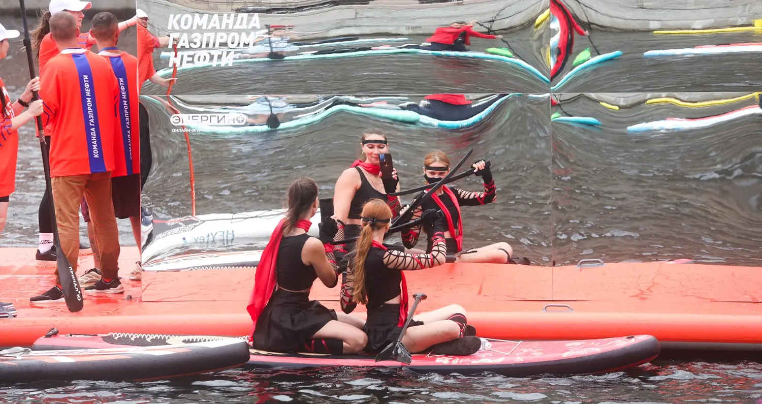 Участники фестиваля «Фонтанка SUP» фотографируют свое отражение в зеркале мегасапа «Энергии+»
