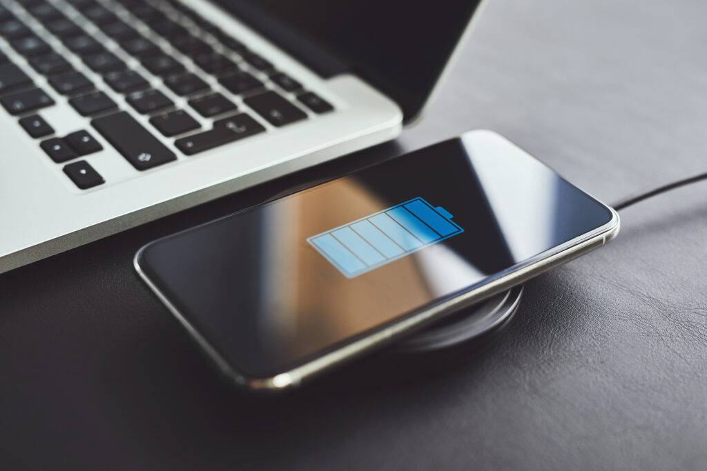 Смартфон во время беспроводной зарядки рядом с ноутбуком