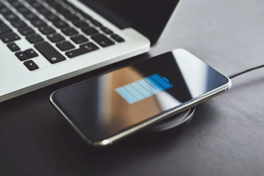 Смартфон во время беспроводной зарядки рядом с ноутбуком