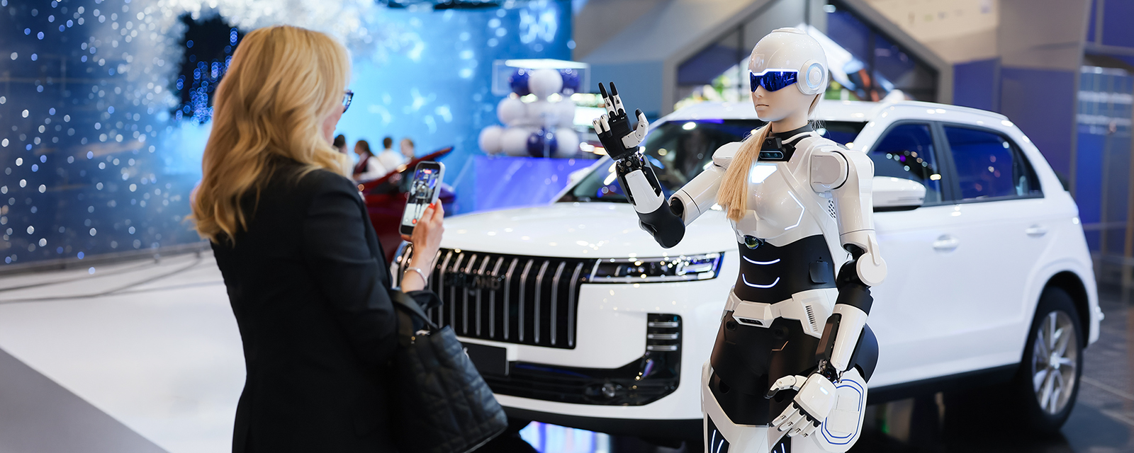 Человекоподобный робот возле нового российского автомобиля на ПМЭФ-2026